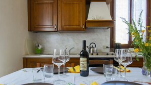 Une table à manger dressée avec des verres à vin, des assiettes et des couverts, ainsi qu’une bouteille de vin et un vase de fleurs posés sur la table.