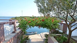 Un escalier menant à un balcon d’où l’on peut admirer la mer et un bateau.