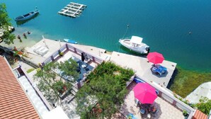 Une vue sur la côte, avec un quai, des bateaux et une terrasse ombragée de parasols.