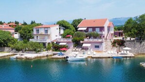 Un village côtier avec des maisons au bord de l’eau, un quai où sont amarrés des bateaux et une vue dégagée sur la mer.