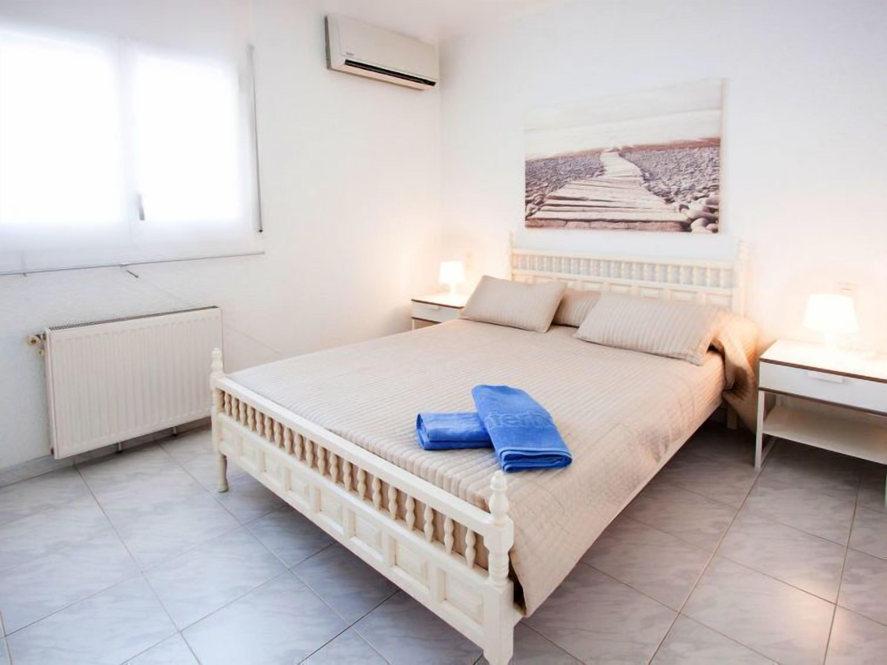 Une chambre à coucher comprenant un lit, deux tables de chevet, un appareil de climatisation et une fenêtre.
