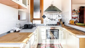 A kitchen with white cabinets, a stove, oven, and a wooden countertop. - On the terraces of Rosa you are constantly forced to look at the sky and Rome (Roma)