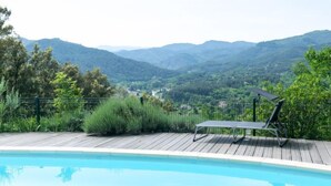 Une piscine avec une terrasse en bois et une chaise longue.