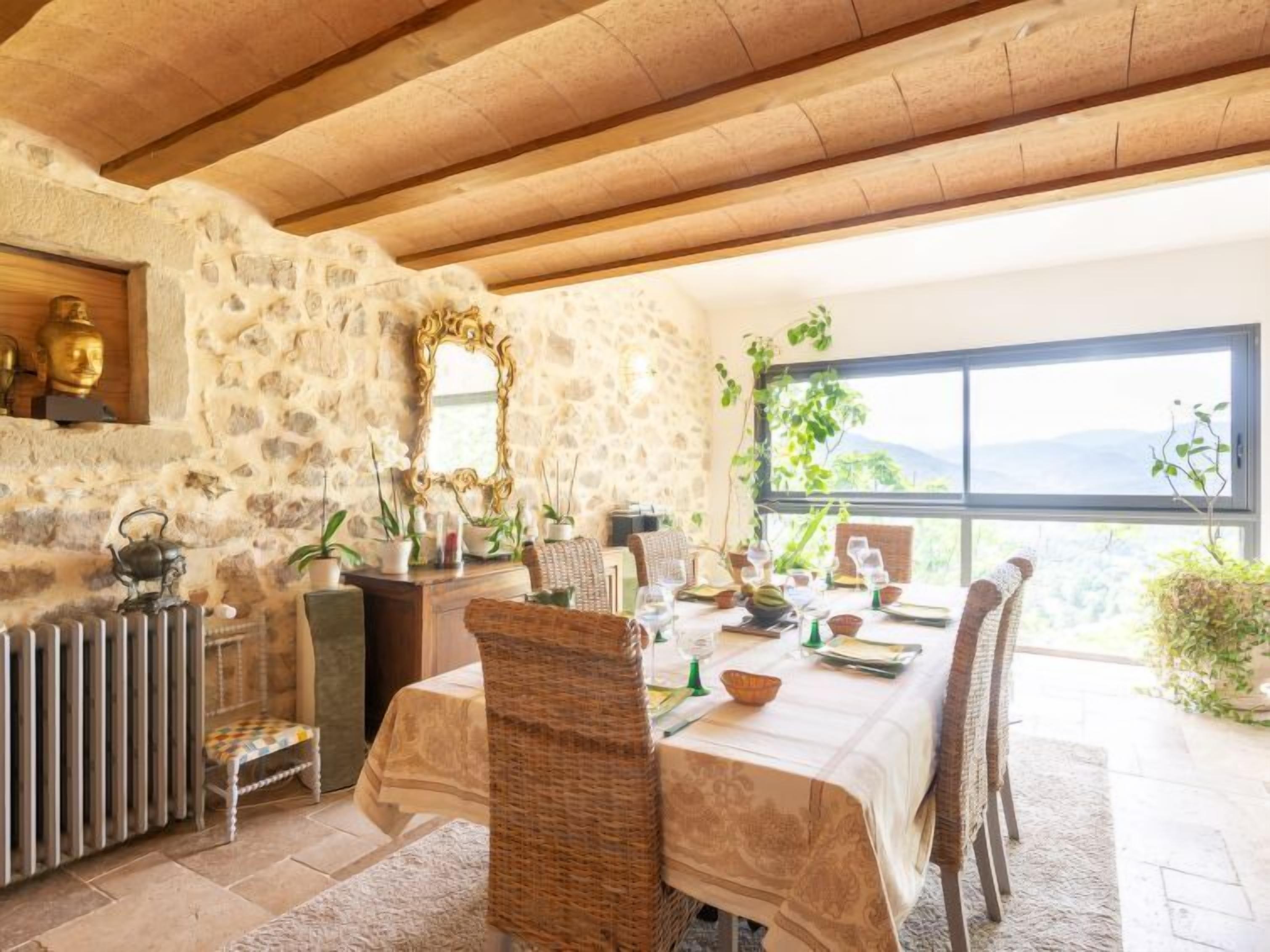 A dining area with a stone wall, a large window, and a view of the outdoors.