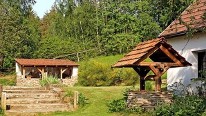 Ein rustikales Steinhaus mit einer Holztreppe, die zu einer überdachten Veranda führt.