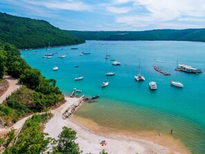 A coastal area with boats docked in calm waters, surrounded by greenery and hills. - Vacation home Gelci by Interhome (Trget)