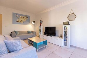 A modern living room with a sofa, coffee table, TV, and a bookshelf.