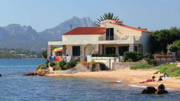 A coastal house with a red-tiled roof, a balcony, and a view of the sea and mountains. - Apartment Paola by Interhome (Cannigione)