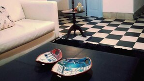 Una habitación con piso a cuadros, un sofá blanco, una lámpara y dos patinetas.