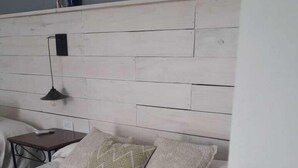 Un dormitorio con cabecera de madera, cama con ropa de cama estampada, mesita de noche y lámpara.