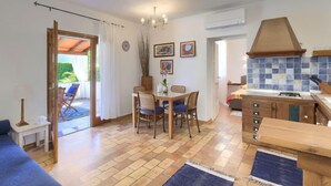 Un salon confortable avec un canapé, un coin repas avec des chaises, une cuisine équipée d’une cuisinière et une vue sur l’extérieur.