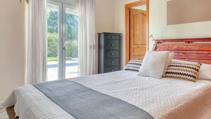 Een slaapkamer met een bed, een kast en een deur naar een balkon.