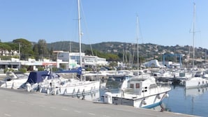 Un port de plaisance où sont amarrés de nombreux bateaux, un ciel dégagé et des bâtiments en arrière-plan.