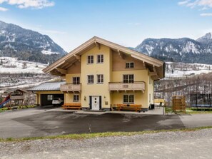 A multi-story building with a sloped roof, balconies, and a parking area in a mountainous region. - Achtalgut by Interhome (Goldegg)