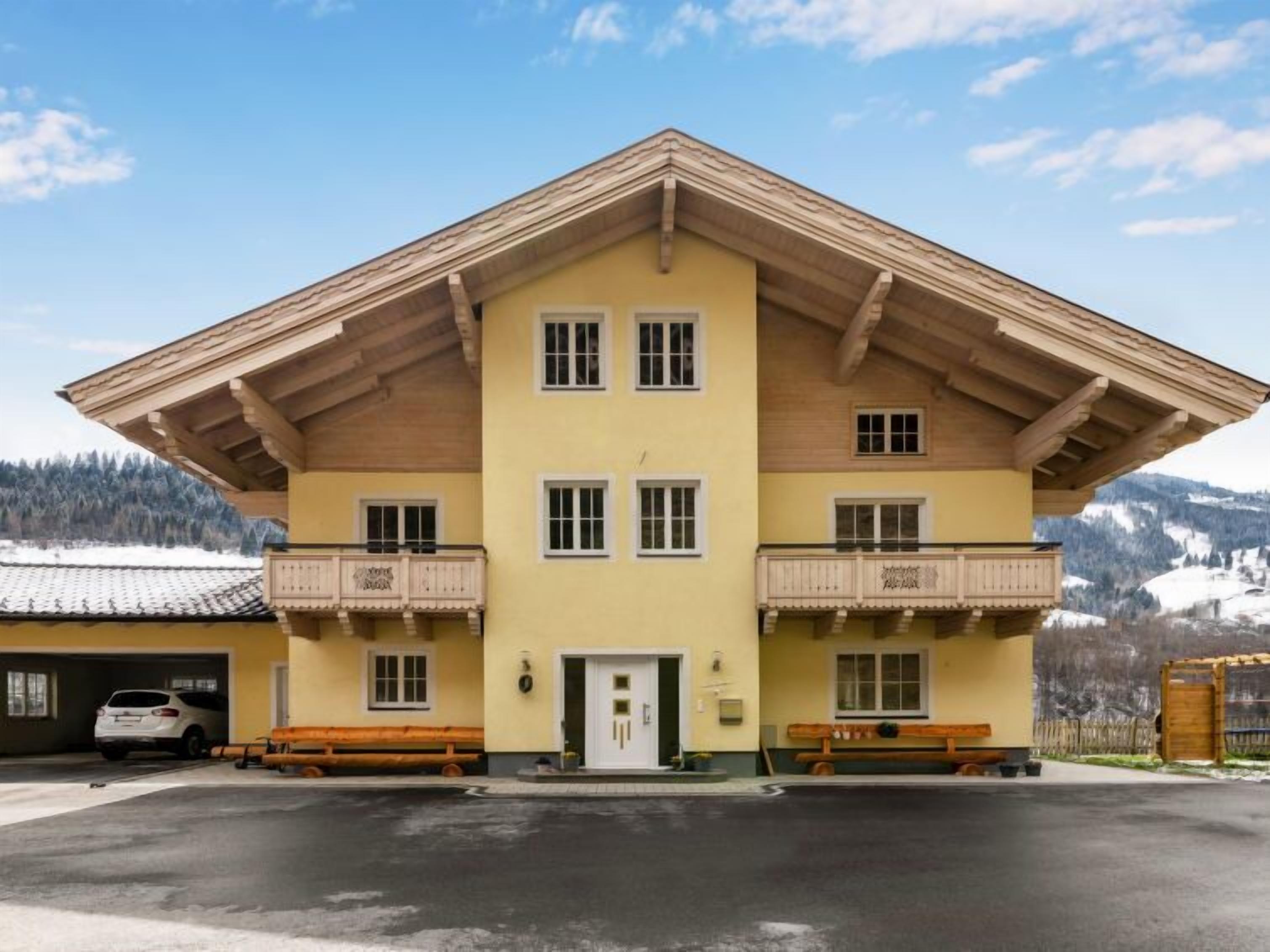 Een gebouw met twee verdiepingen, een schuin dak, balkons en een garage.