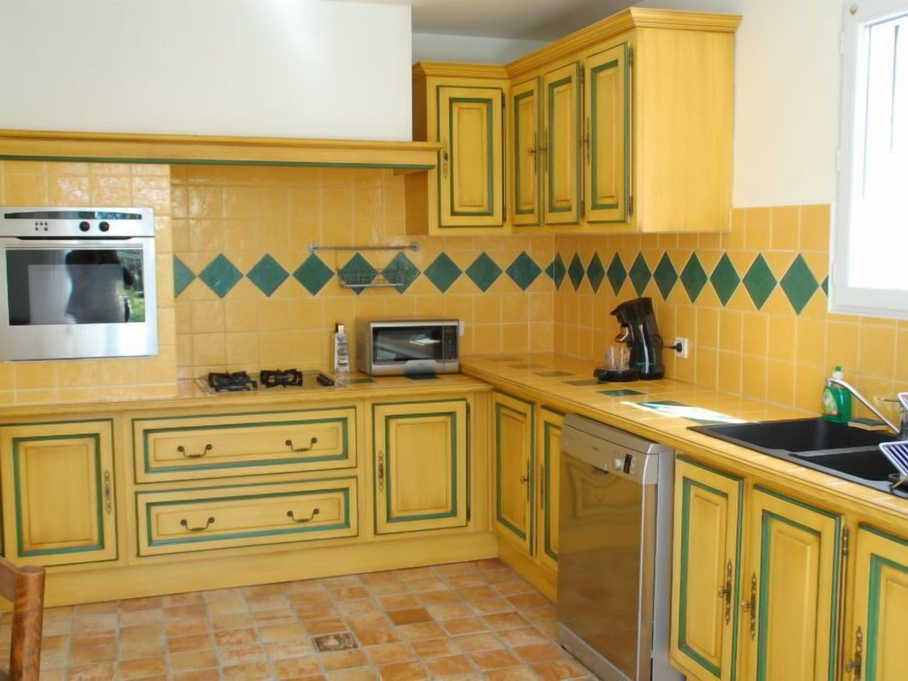 A compact kitchen with yellow cabinets, a built-in oven, a microwave, and a dishwasher.