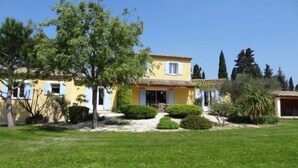 A yellow villa with a tiled roof, surrounded by a well-maintained lawn and various trees. - Siflora by Interhome (Saint-Rémy-de-Provence)