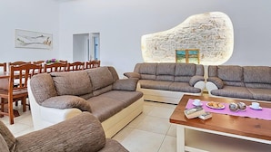 A living room with a stone wall accent, a dining area with wooden furniture, and a coffee table with pastries.