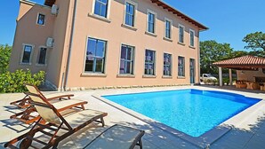 A two-story building with a swimming pool, outdoor seating, and a covered area.