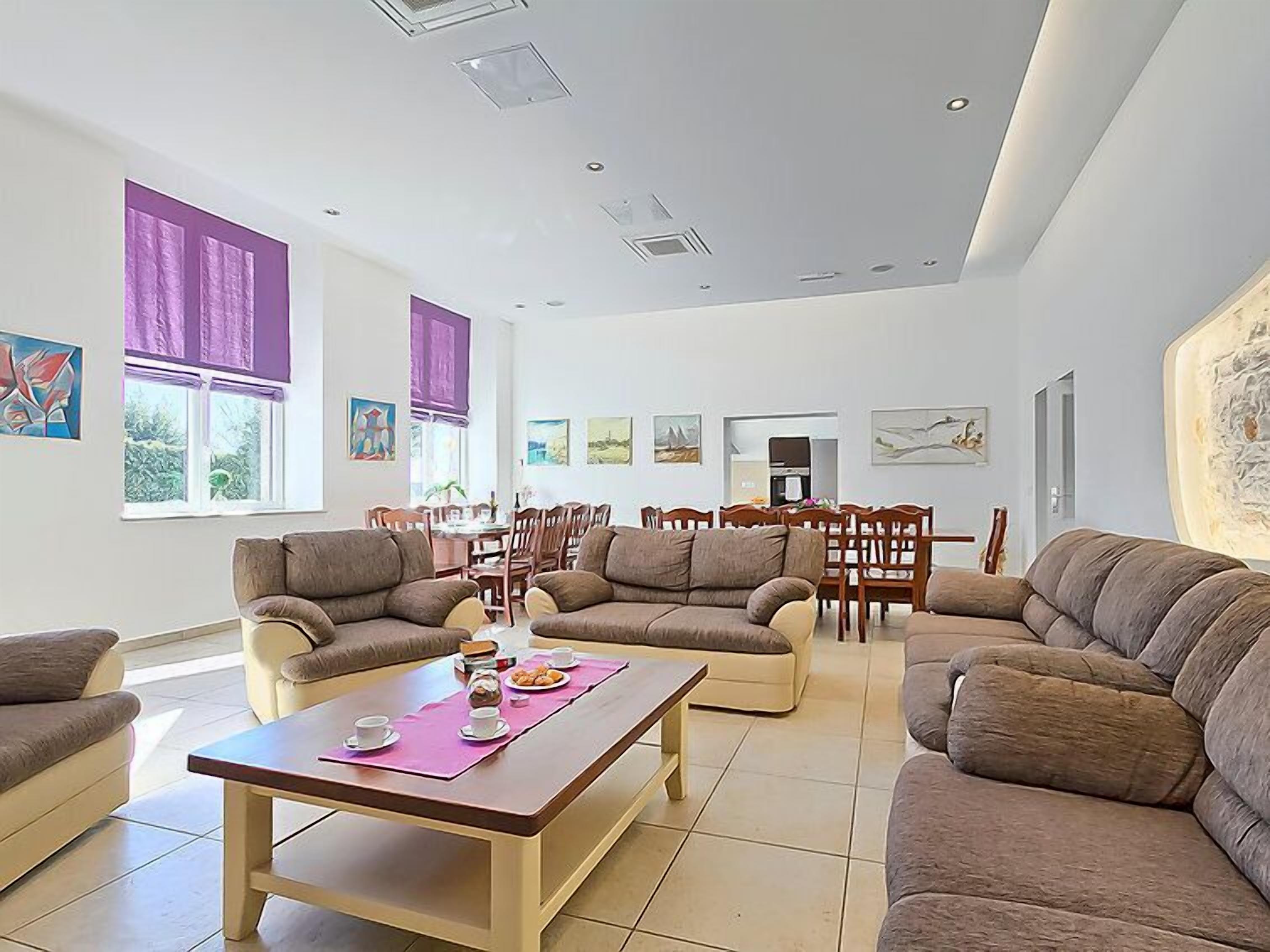 A spacious living room with multiple sofas, a dining area, and artwork on the walls.