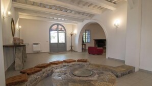 A spacious living area with a stone fireplace, a red sofa, and a large arched doorway.