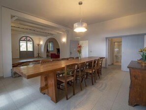 Un comedor amplio con una larga mesa de madera y sillas, una lámpara colgante y vistas a un patio exterior.