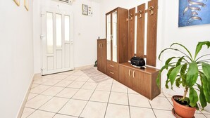 A hallway with a wooden wardrobe, a potted plant, and a door with a cross on it. - Apartment Tino by Interhome (Pag/Pag)
