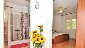 A hotel room with a shower, a bed, a ceiling fan, and a vase with sunflowers. - Apartment Tino by Interhome (Pag/Pag)
