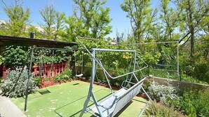 A garden with a swing set, a small lawn, and various plants. - Apartment Tino by Interhome (Pag/Pag)
