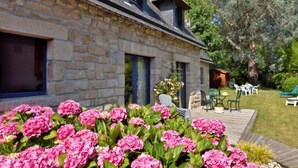 A stone house with a deck, surrounded by a garden with pink flowers. - St Adrien by Interhome (Ploemeur)