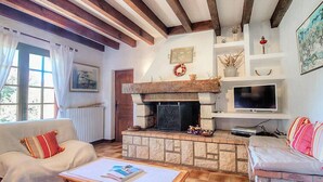 Una sala de estar acogedora con chimenea de piedra, un televisor y un rincón de descanso con dos sofás.