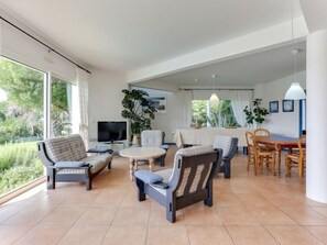A spacious living area with a sofa, chairs, a TV, and a dining table.