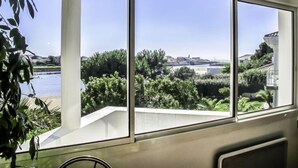 A room with large windows overlooking a body of water and greenery. - Les Pinasses by Interhome (Mimizan)