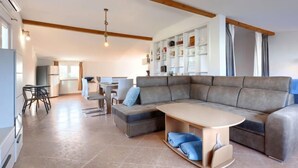 A modern living room with a sectional sofa, a dining area, and a kitchen in the background. - Vacation home Finida by Interhome (Umag)