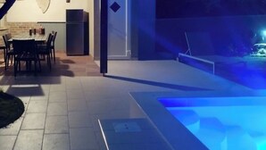An outdoor patio with a pool, a dining area, and a brick wall. - Vacation home Finida by Interhome (Umag)
