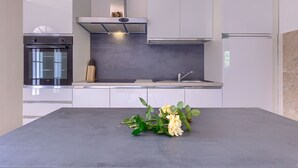 A modern kitchen with white cabinets, a built-in oven, and a stainless steel range hood. - Vacation home Finida by Interhome (Umag)