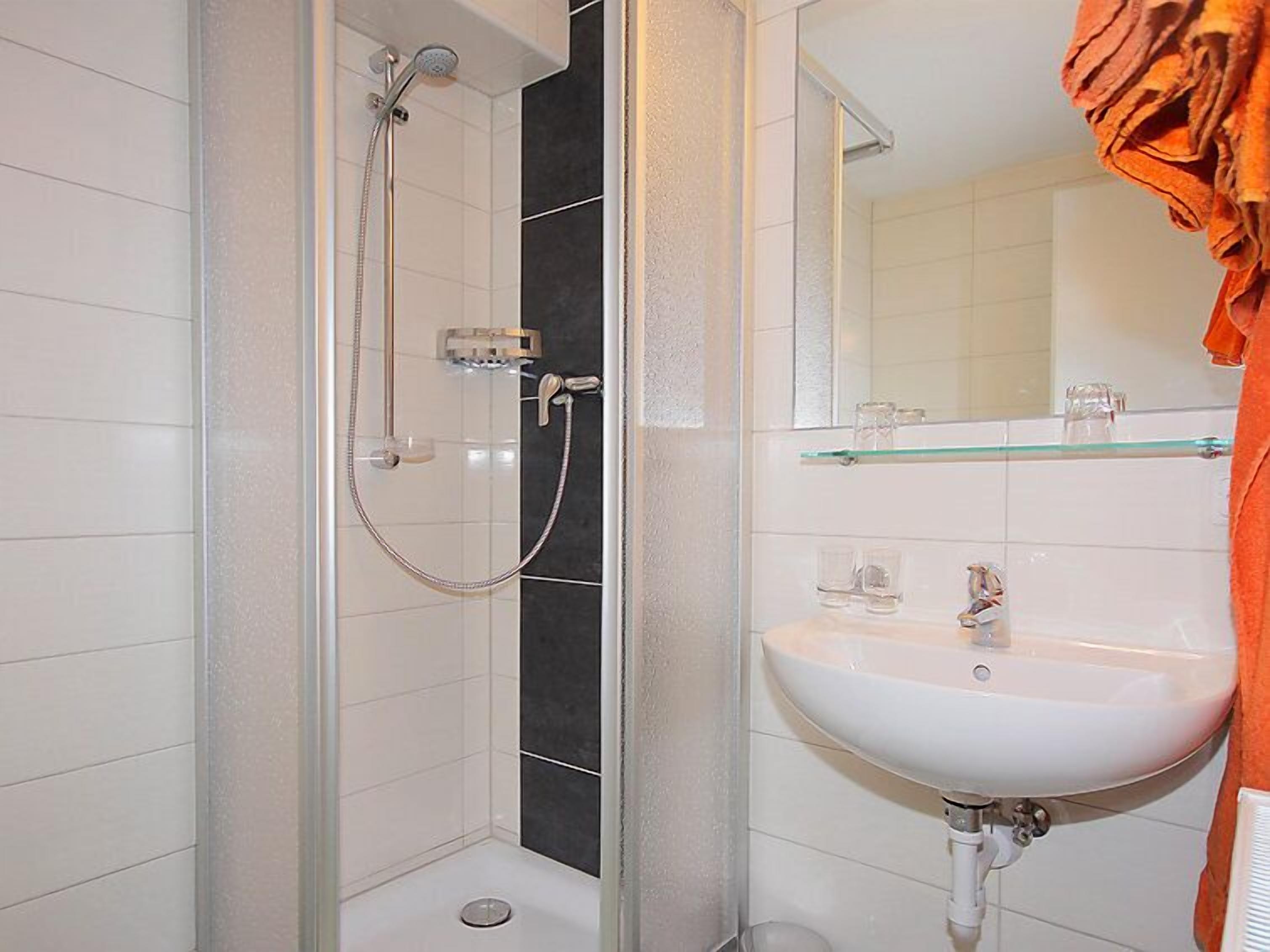 Un bagno con doccia, lavandino e specchio.