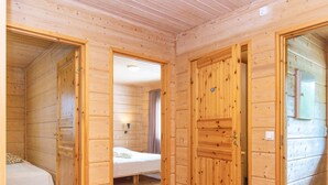A wooden cabin room with a bed, a small table, and a window. - Hot pool cottage ainu by Interhome (Enonkoski)
