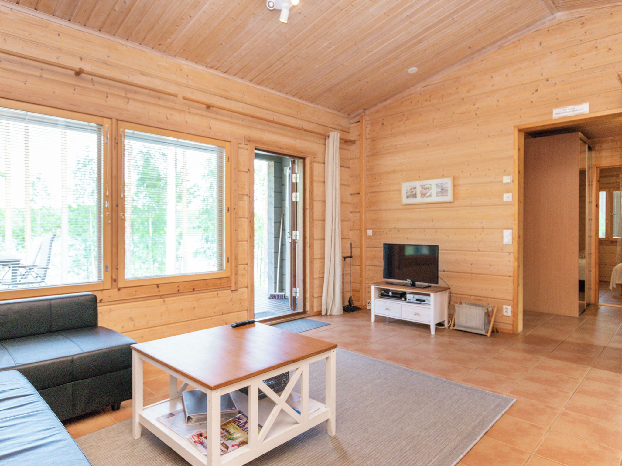 A wooden interior with a sofa, a TV stand, and a table.