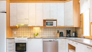 A modern kitchen with white cabinets, a microwave, an oven, and a dishwasher. - Hot pool cottage ainu by Interhome (Enonkoski)