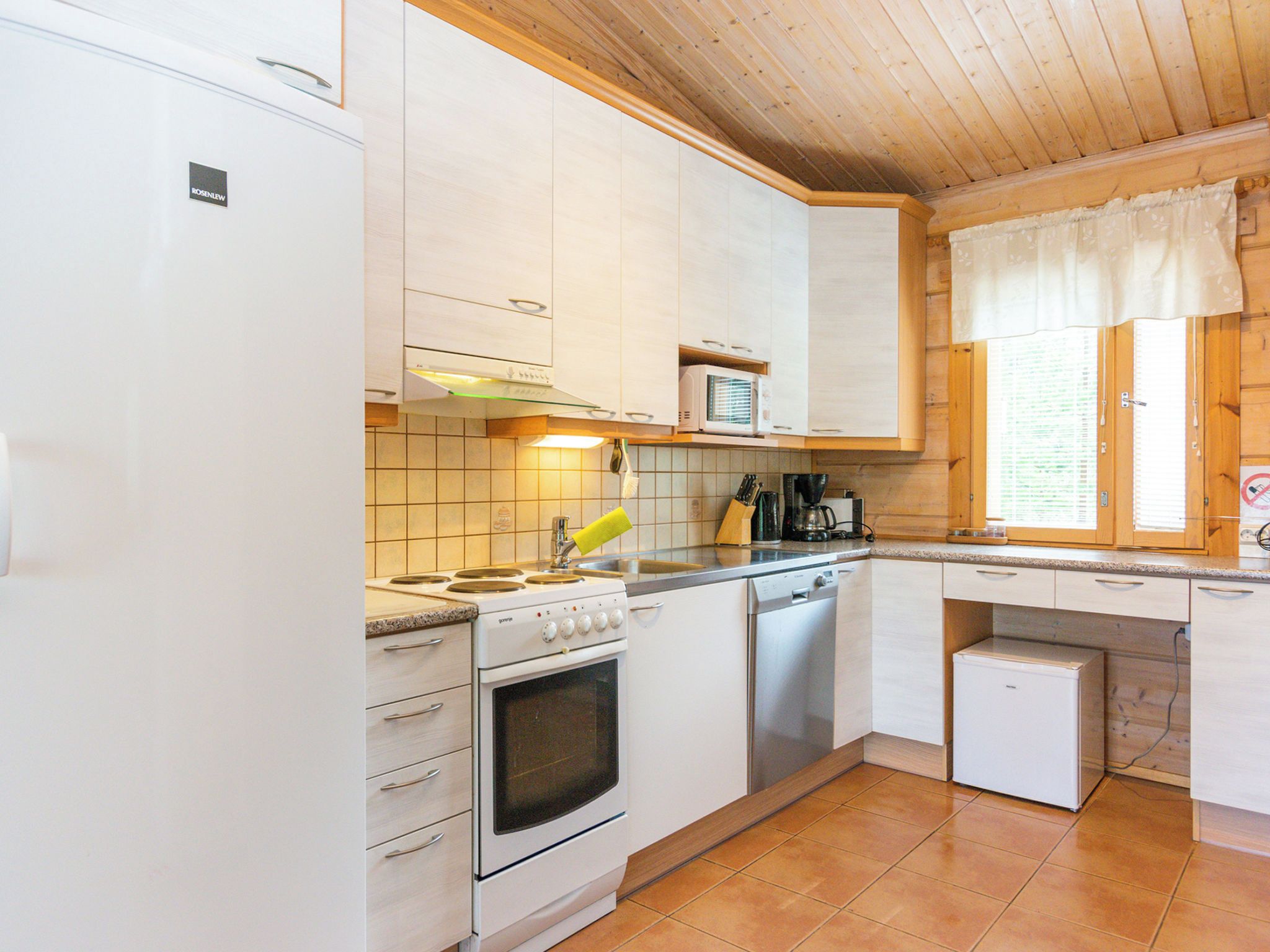A compact kitchen with white cabinetry, a stove, a microwave, and a small refrigerator.