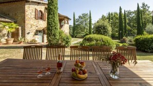 A wooden table set outdoors with a bottle, glasses, and fruit. - Tenuta Farneta by Interhome (Lucignano)