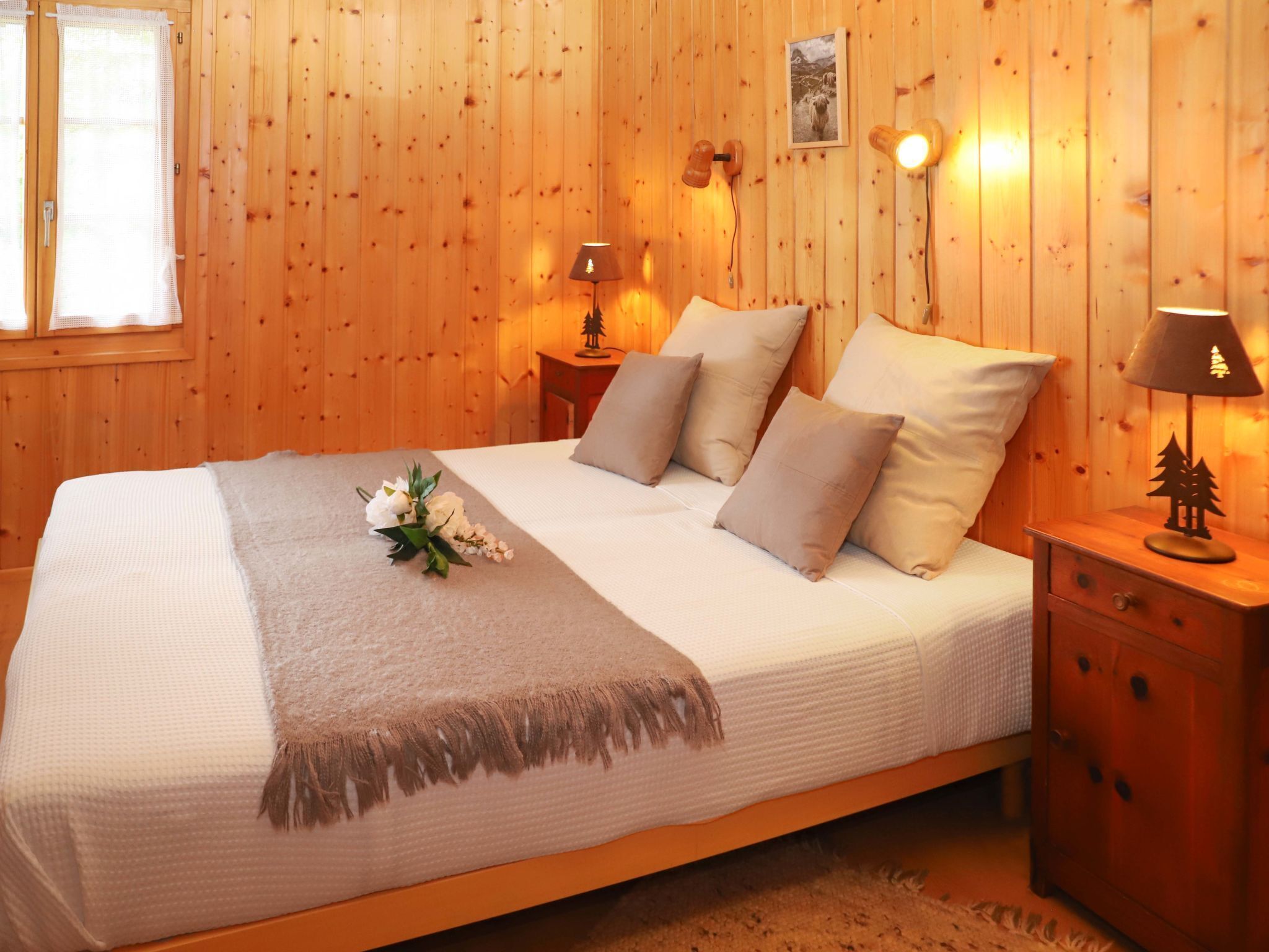 Un dormitorio con paneles de madera, una cama, almohadas, una mesita de noche y una lámpara.