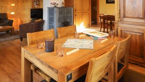Een houten eettafel met een spel, glaasjes en een kaars.