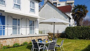 A modern house with a stone facade, a balcony with a railing, and a dining area with a table and chairs. - La Coloniale by Interhome (Auray)