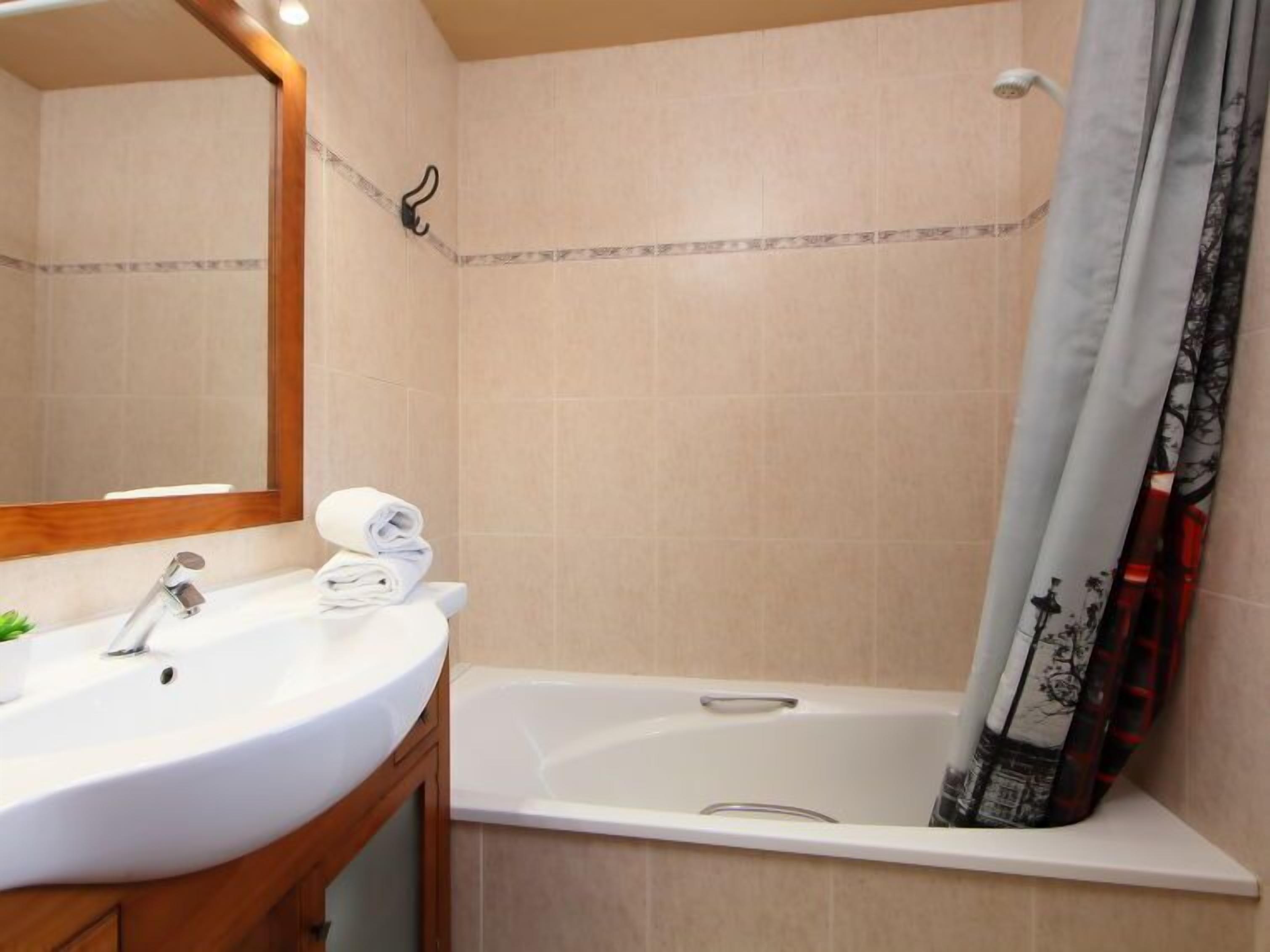 A bathroom with a sink, mirror, and bathtub.