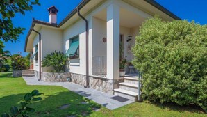 Una casa de dos plantas con base de piedra, un porche cubierto y un jardín bien cuidado.