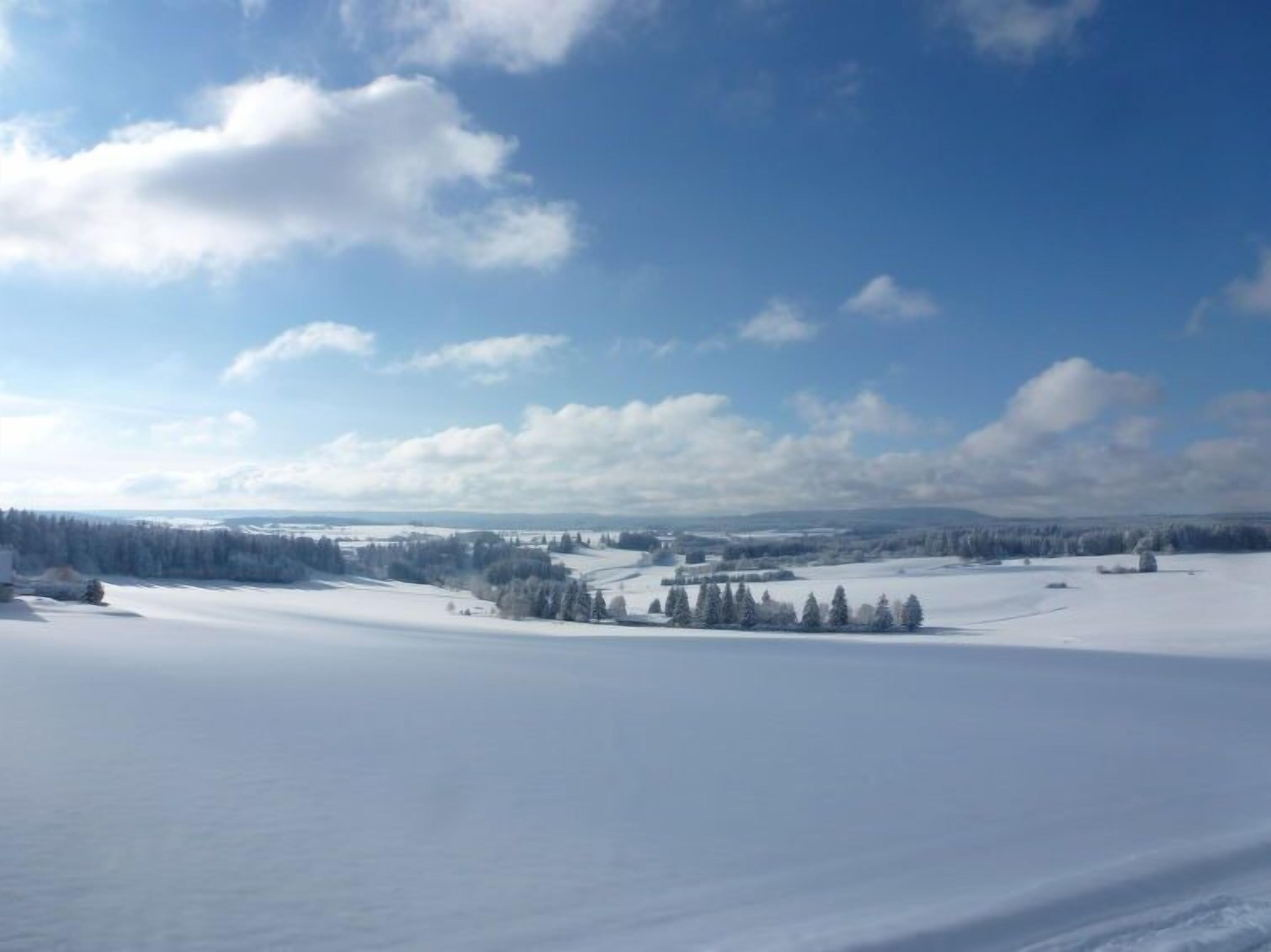 Paesaggio innevato con cielo sereno e edifici in lontananza.