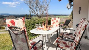 An outdoor patio with a table and chairs, a bottle of wine, and a view of the countryside. - Schöne Aussicht by Interhome (Dittishausen)