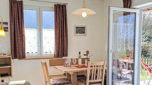A cozy room with a wooden dining table, two chairs, a sofa, and a sliding glass door leading to an outdoor area. - Schöne Aussicht by Interhome (Dittishausen)